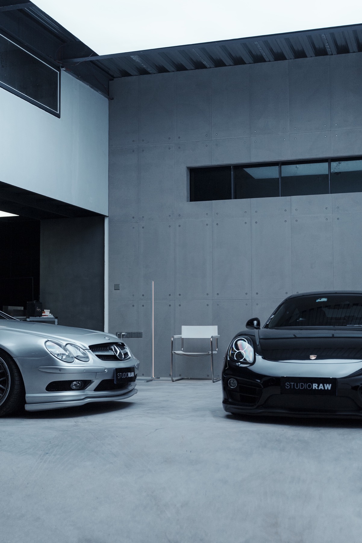 Two cars and white chair against concrete wall